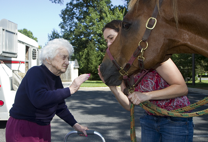 Wellspring Village Dementia Care Resident petting horse visiting Brightview with horse owner